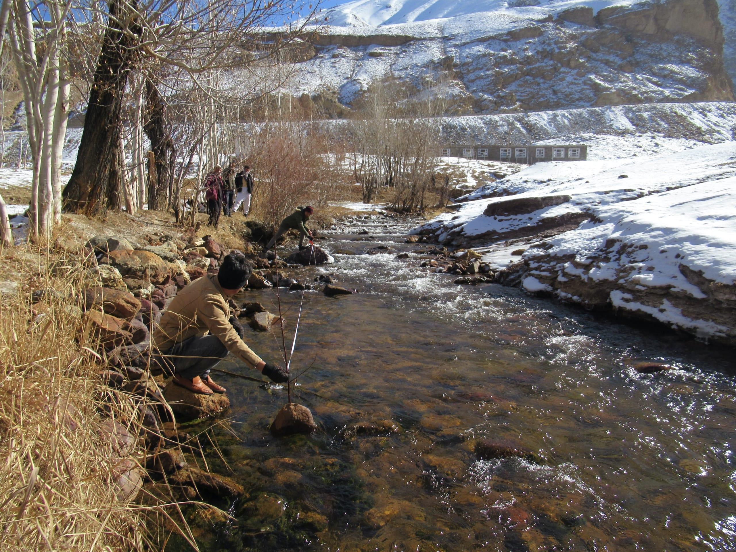 Two men measure the velocity of the river flow.